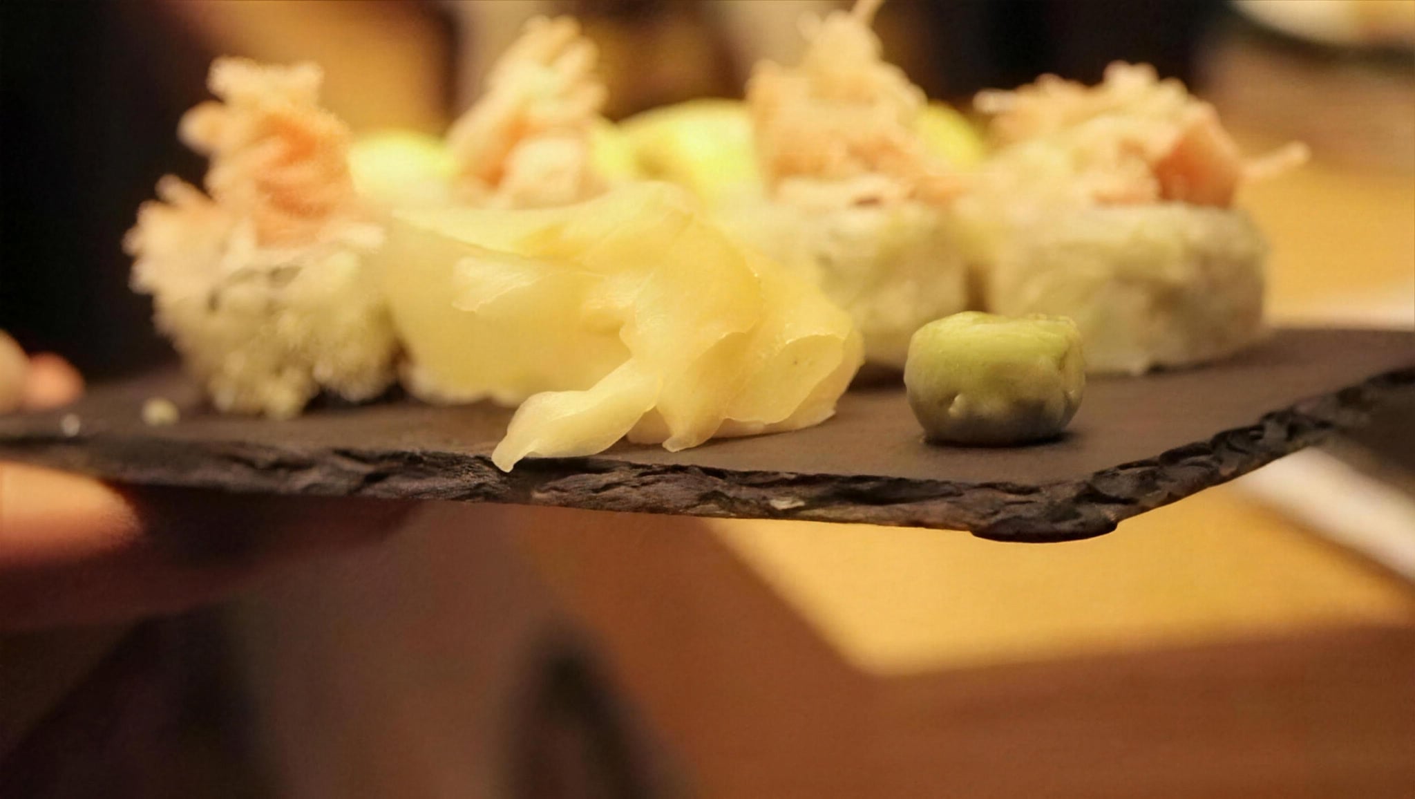 Sushi rolls with pickled ginger and wasabi on a slate board
